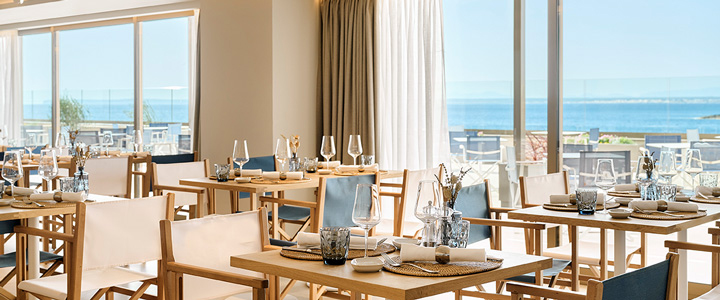 Elegantes Restaurant mit Meerblick und stilvoll gedeckten Tischen, harmonisch gestaltet in Beige- und Blautönen